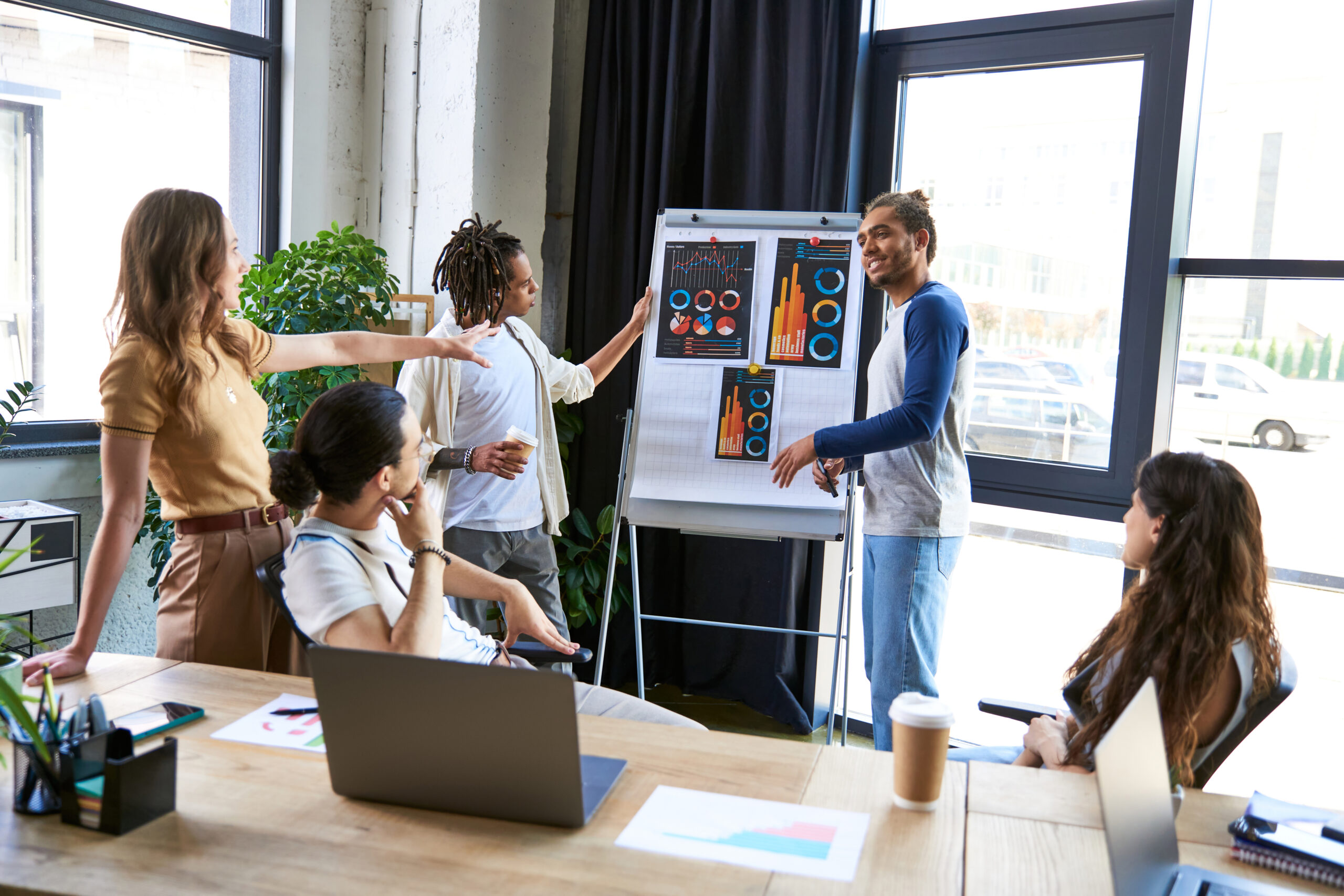 creative multiethnic team talking and sharing ideas near flip chart with  infographics in office